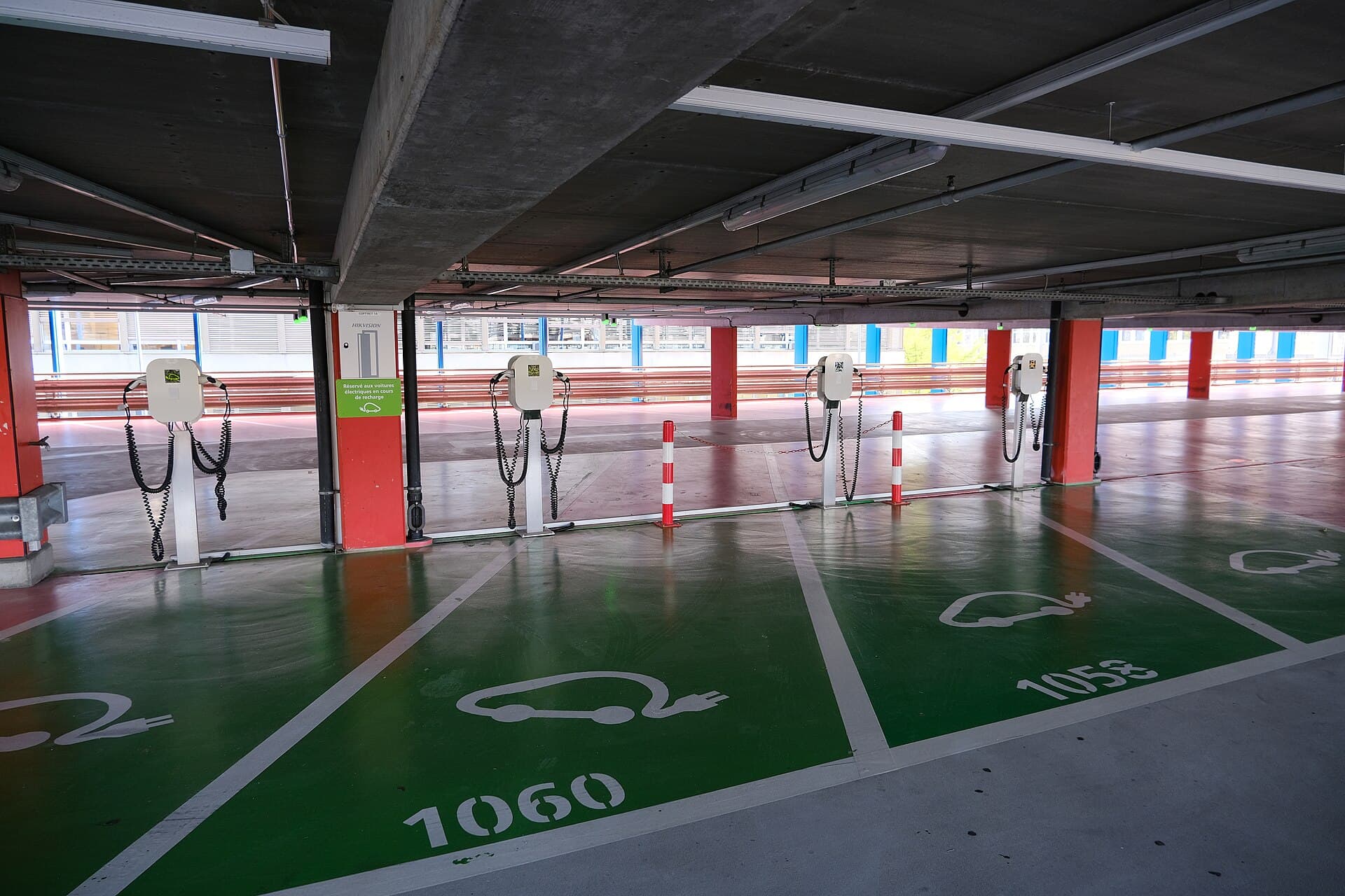 Places de recharge peintes en vert dans un parking couvert, bornes murales